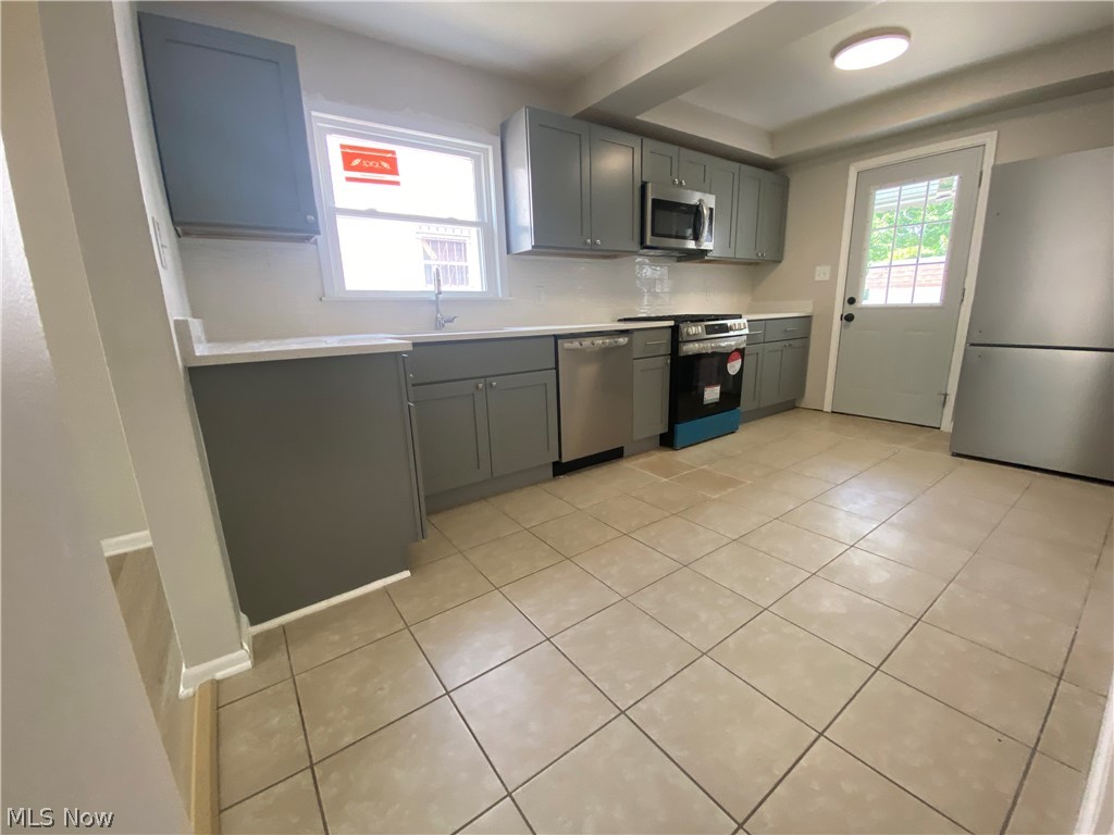 13117 Silver Road Garfield Heights, OH 44125 - Photo 7 of 20 Kitchen with gray cabinetry, light tile flooring, and appliances with stainless steel finishes