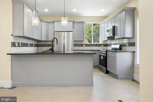 a kitchen with kitchen island granite countertop a sink a counter space appliances and cabinets
