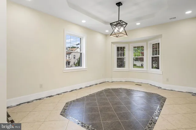 a view of an empty room with window and chandelier fan