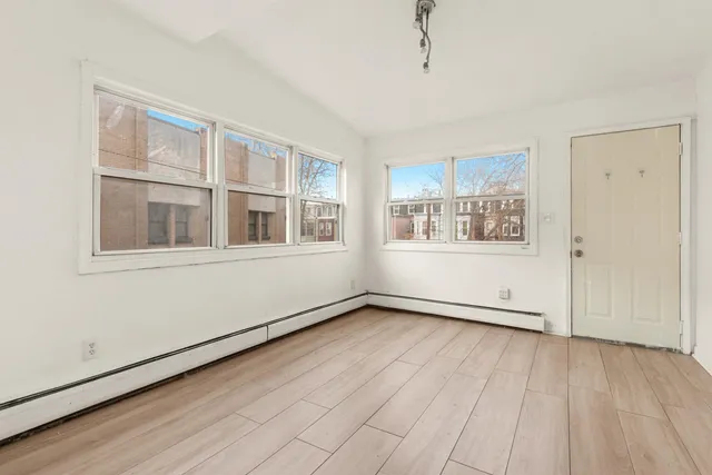 a view of an empty room with a window and wooden floor