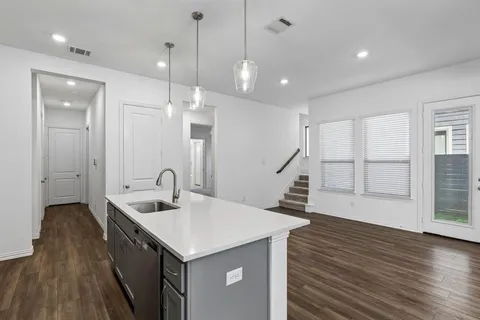 a kitchen with a sink a faucet a chandelier and wooden floor