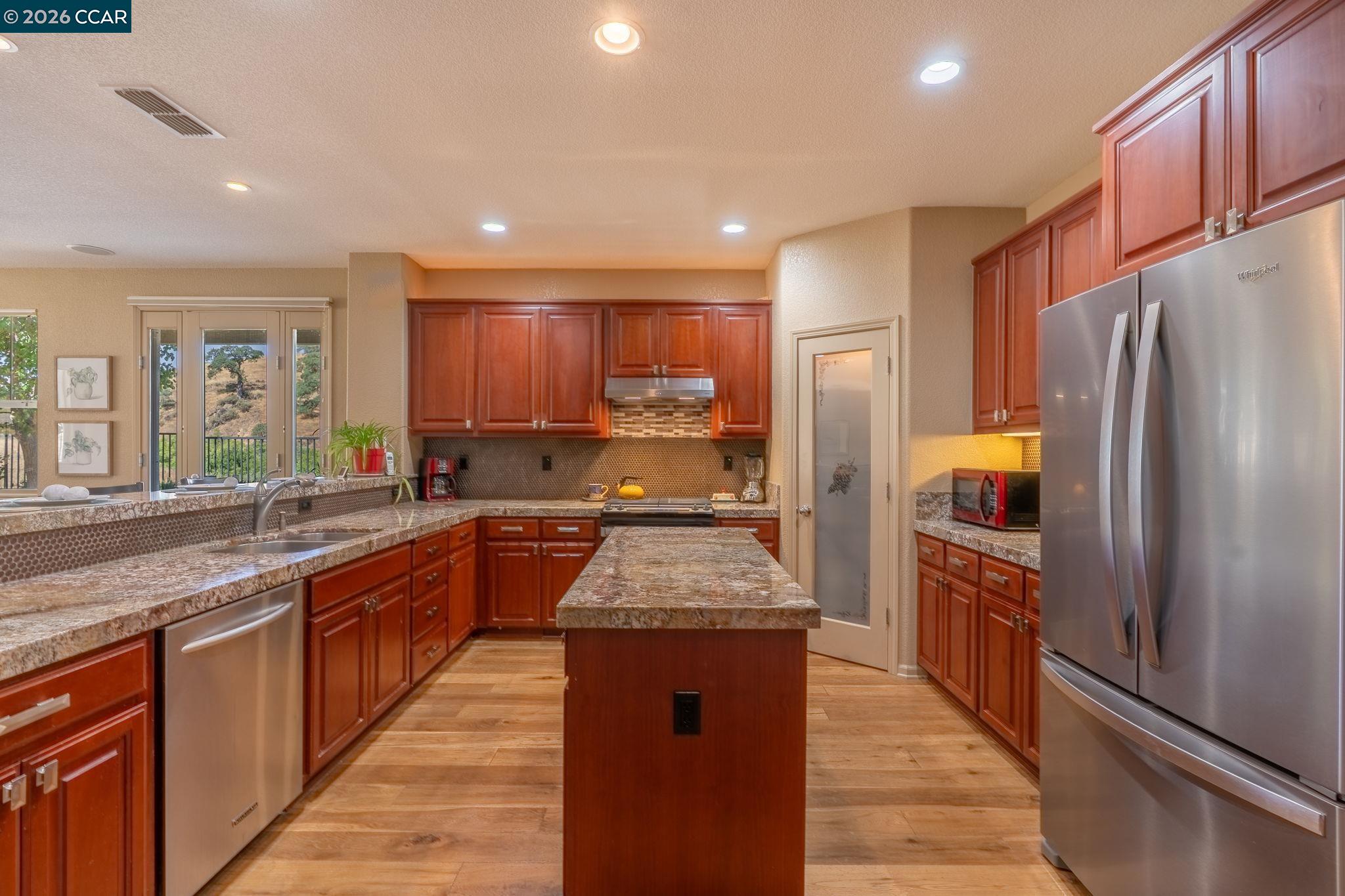 9028 Tee Court Patterson, CA 95363 - Photo 8 of 40 a large kitchen with stainless steel appliances granite countertop a refrigerator and a sink