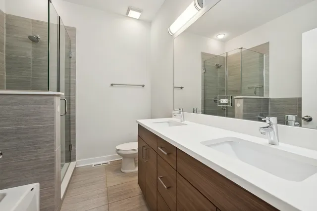 a bathroom with a double vanity sink toilet and shower