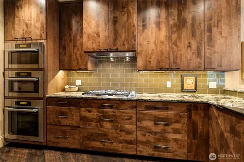 a kitchen with a stove a sink dishwasher a dining table and chairs with wooden floor