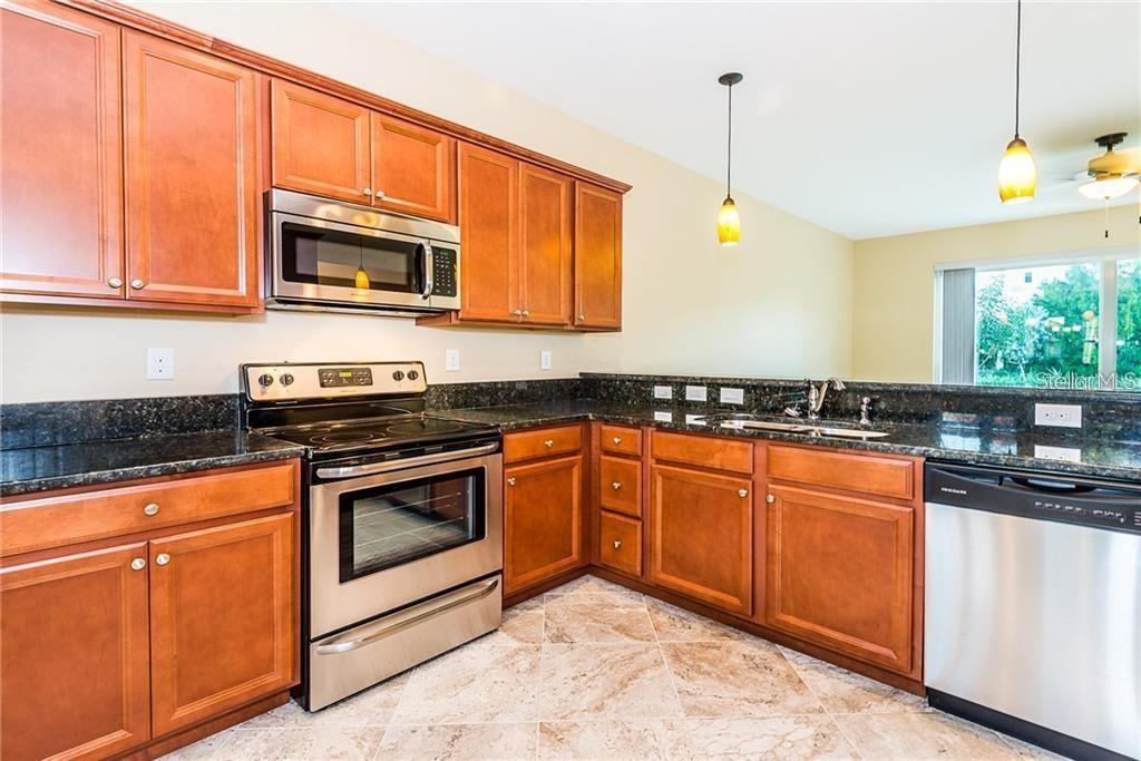3948 San Rocco Drive, Unit 112 Punta Gorda, FL 33950 - Photo 9 of 18 a kitchen with stainless steel appliances granite countertop a stove a sink and a microwave