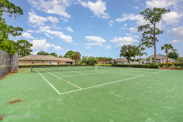 a view of a tennis ground with huge green field and trees