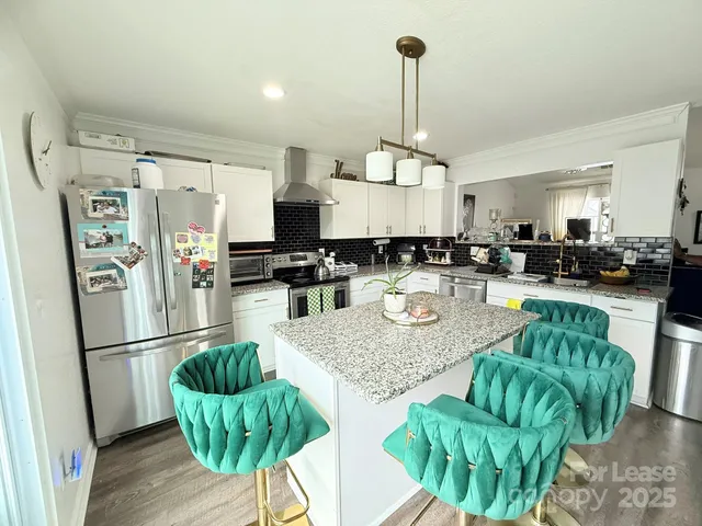 a kitchen with stainless steel appliances granite countertop a refrigerator sink and chairs