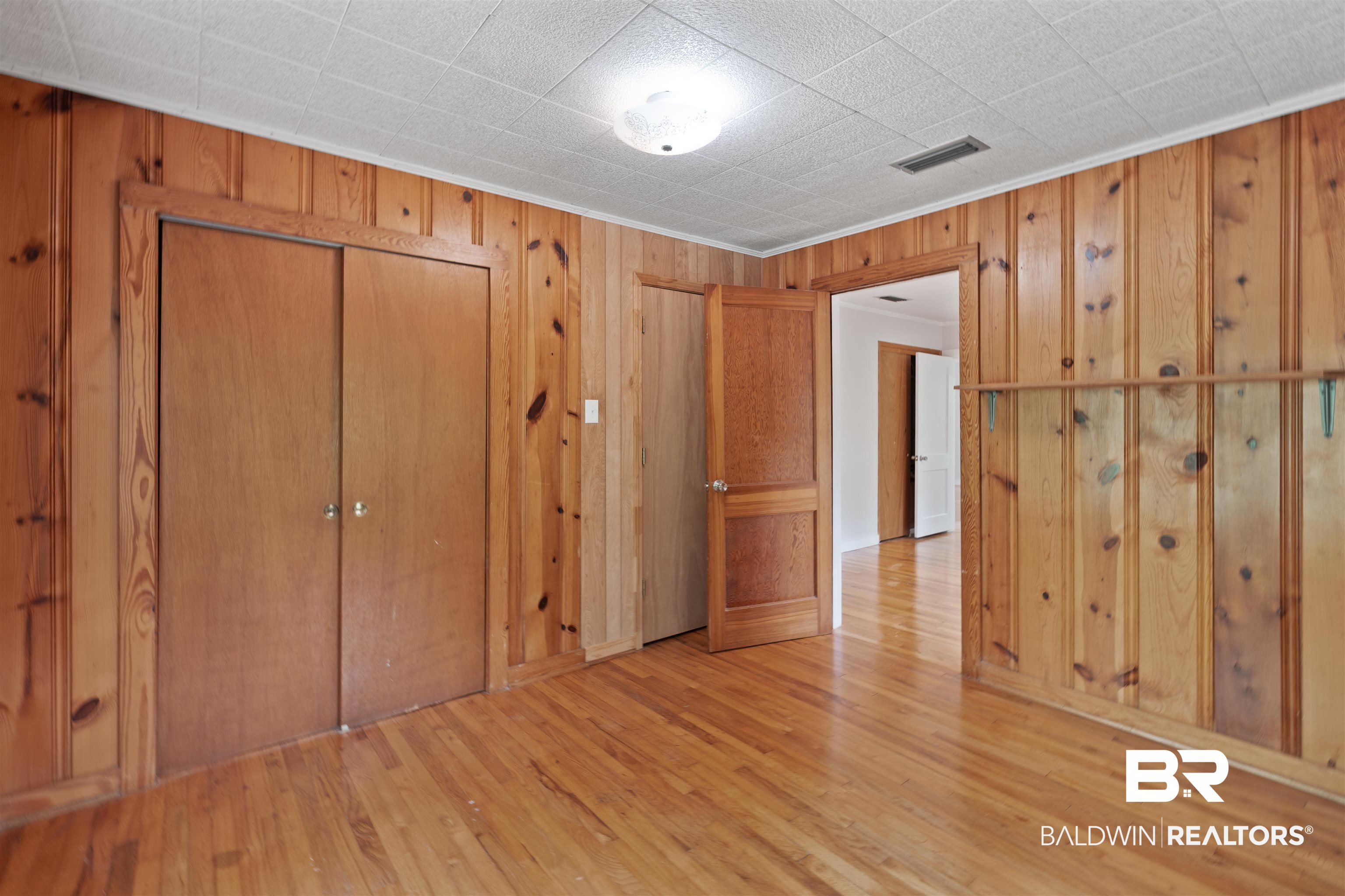 2126 Barron Place Mobile, AL 36605 - Photo 17 of 33 Unfurnished bedroom with a closet, wooden walls, light hardwood / wood-style floors, and crown molding