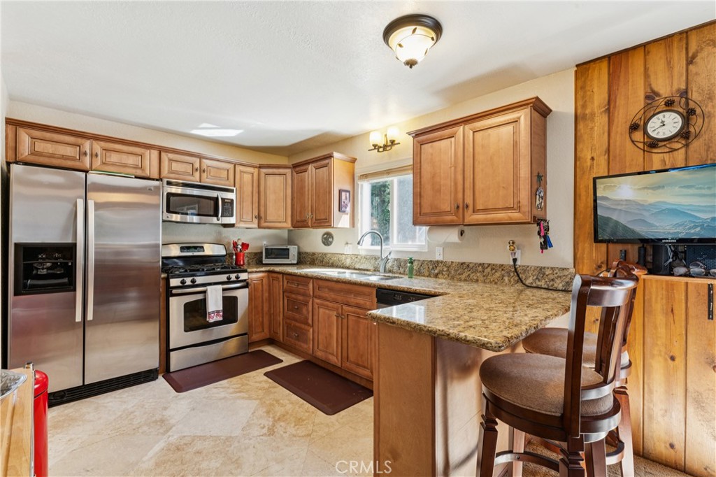 460 Pioneer Road Lake Arrowhead, CA 92352 - Photo 12 of 48 a kitchen with stainless steel appliances granite countertop a stove refrigerator sink and cabinets