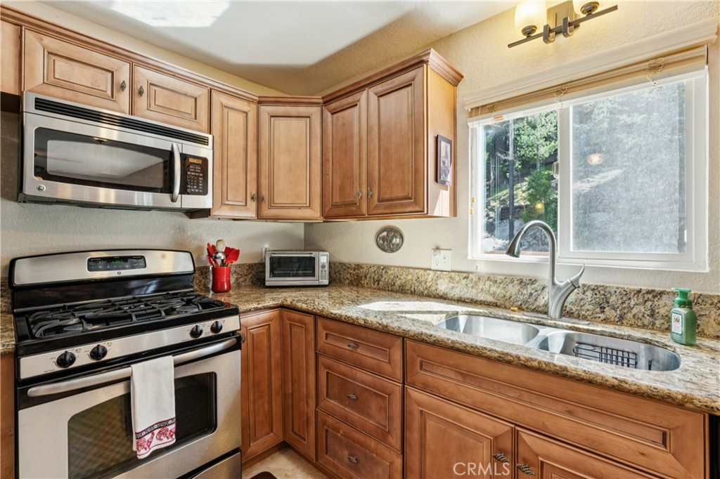 460 Pioneer Road Lake Arrowhead, CA 92352 - Photo 13 of 48 a kitchen with granite countertop a stove a sink and a microwave