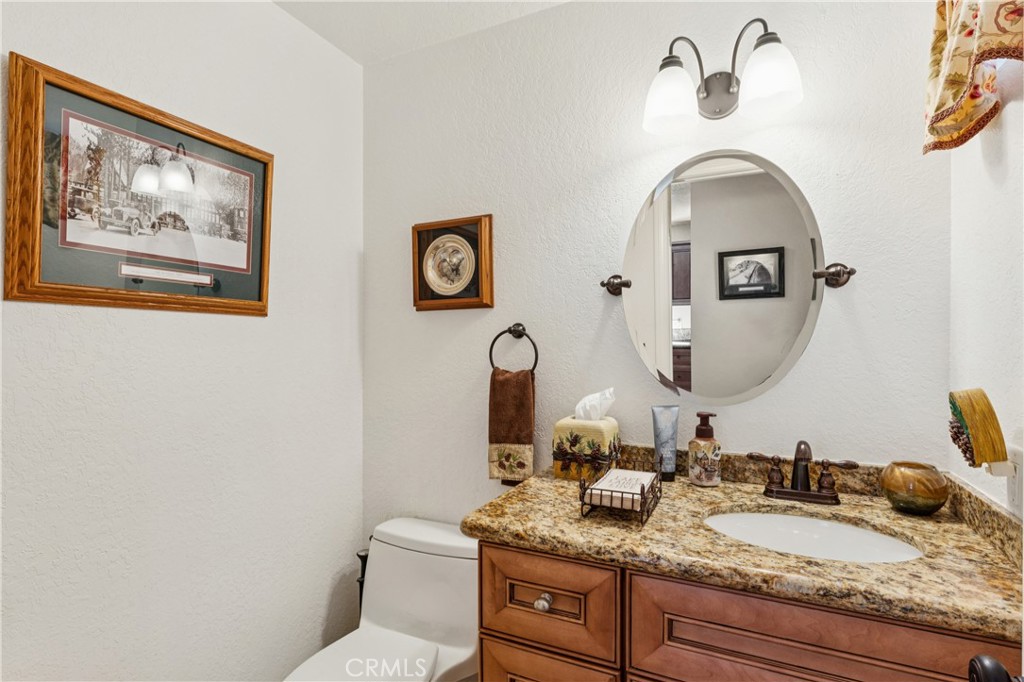 460 Pioneer Road Lake Arrowhead, CA 92352 - Photo 41 of 48 a bathroom with a granite countertop toilet a sink and a mirror