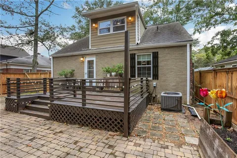 a view of a backyard with table and chairs potted plants and large tree