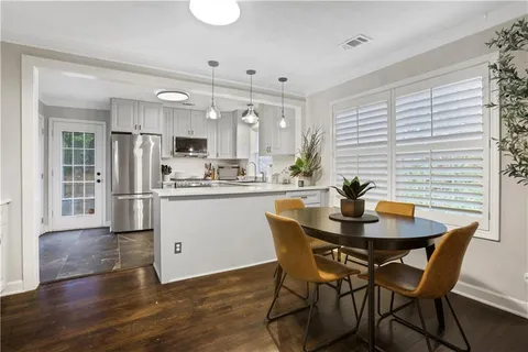 a kitchen with stainless steel appliances kitchen island granite countertop a dining table chairs and a refrigerator