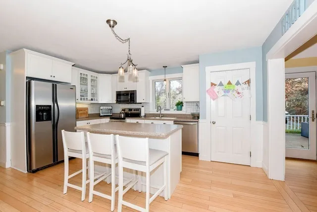 a kitchen with stainless steel appliances granite countertop a refrigerator a microwave oven a refrigerator a sink and dishwasher with wooden floor