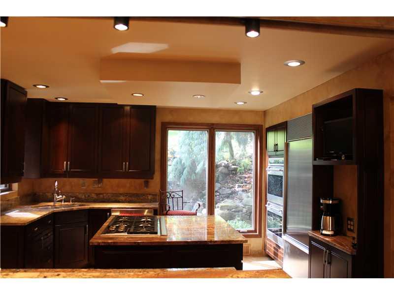 Kitchen. resort like view from the granite kitchen counter to picture window that frames waterfall/pond