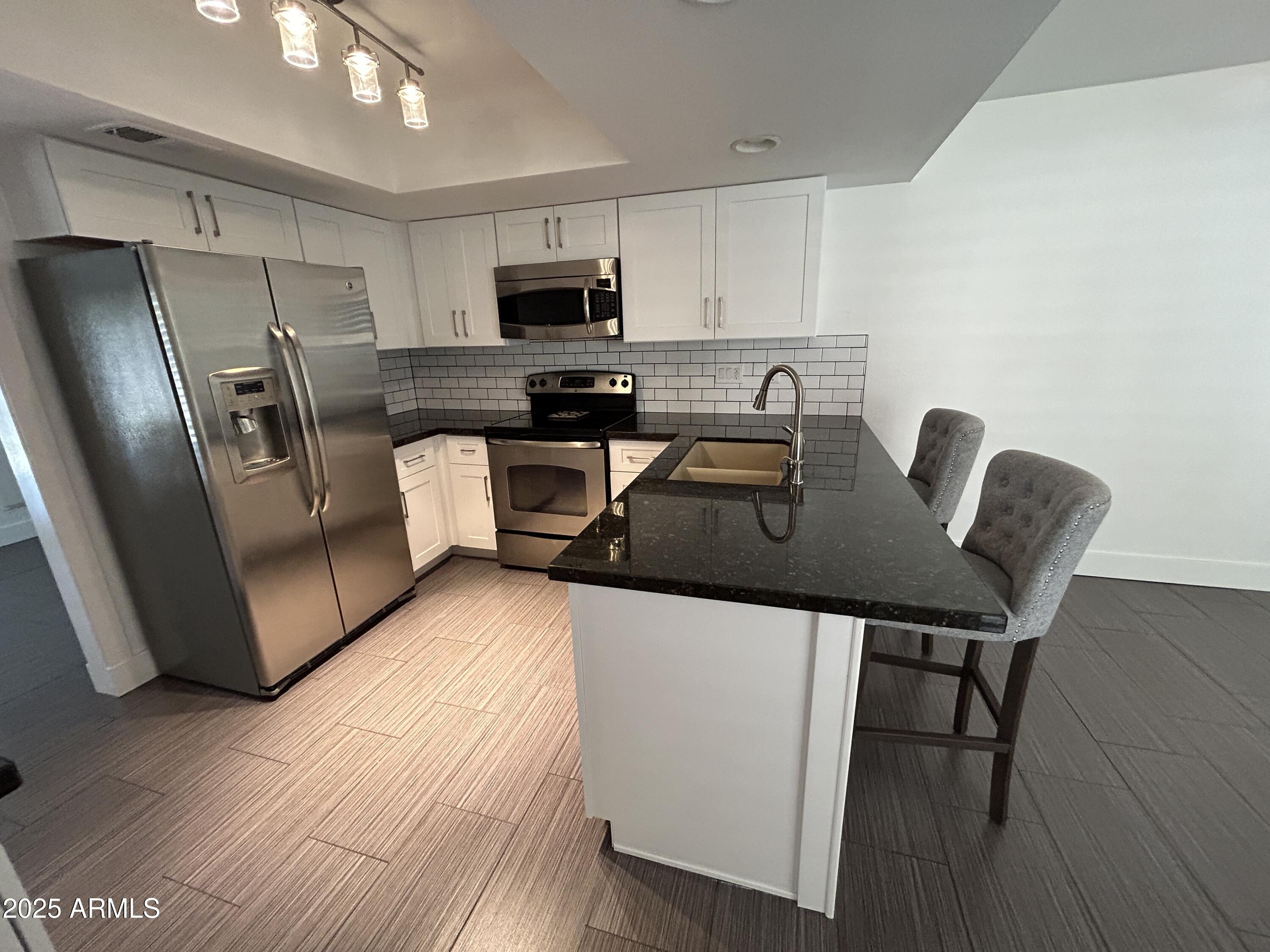 320 East Larkspur Lane Tempe, AZ 85288 - Photo 1 of 16 a kitchen with stainless steel appliances a refrigerator a stove a sink a dining table and chairs with wooden floor