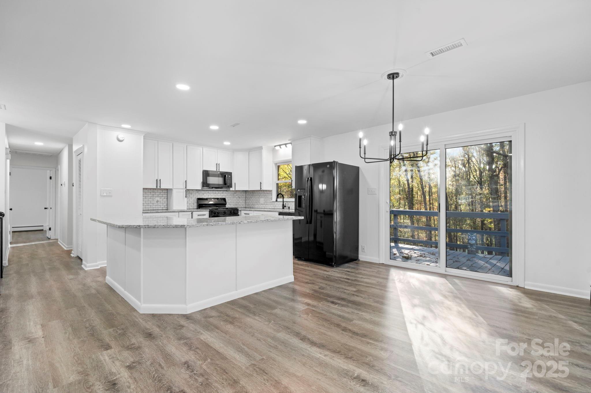 1185 10th St Pl Circle Northwest Hickory, NC 28601 - Photo 5 of 38 a kitchen with stainless steel appliances kitchen island granite countertop a refrigerator a oven a sink and a wooden floor