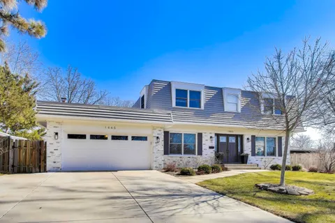 a front view of a building with garden and trees