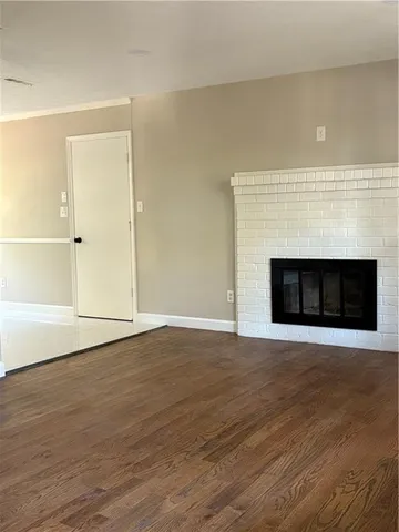 a view of an empty room with wooden floor and a fireplace