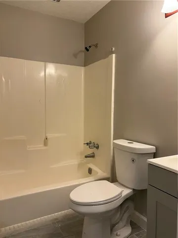 a view of an empty room with wooden floor and fan