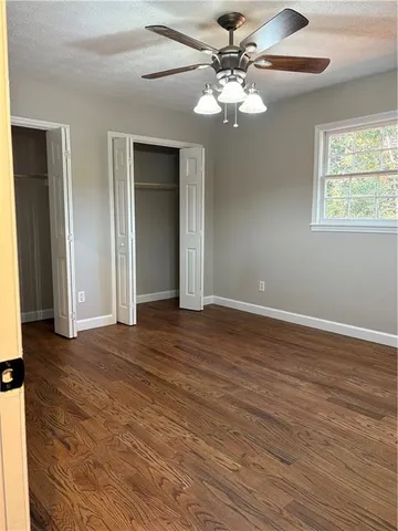 a view of an empty room with a window and wooden floor