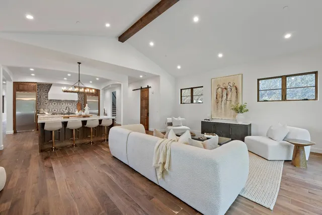 a living room with furniture a large window and wooden floor