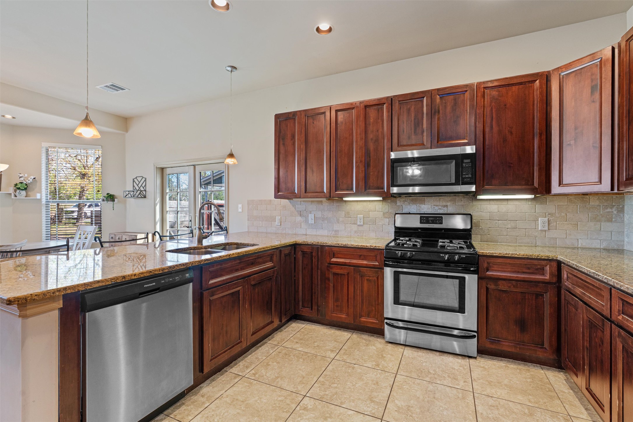209 Harris Street Elgin, TX 78621 - Photo 8 of 40 Kitchen with stainless steel appliances, light stone countertops, a peninsula, and hanging light fixtures