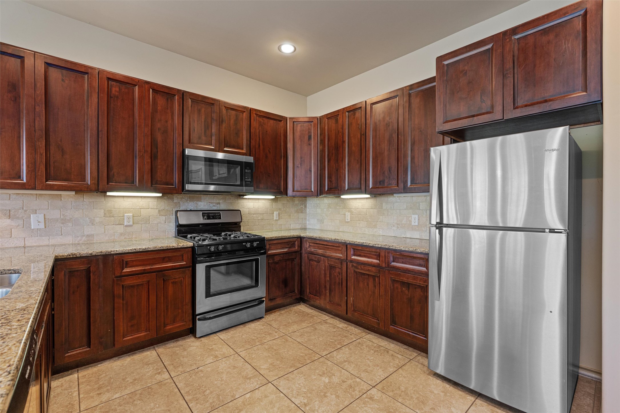 209 Harris Street Elgin, TX 78621 - Photo 9 of 40 Kitchen featuring stainless steel appliances, light stone counters, light tile patterned floors, and backsplash