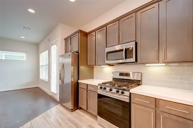a kitchen with cabinets stainless steel appliances and wooden floor