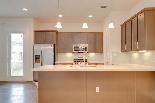 a kitchen with kitchen island a large counter top space a sink stainless steel appliances and cabinets