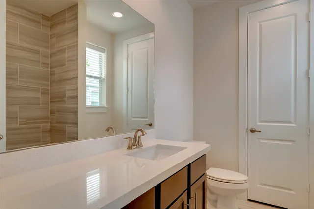a bathroom with a granite countertop sink a toilet and a mirror