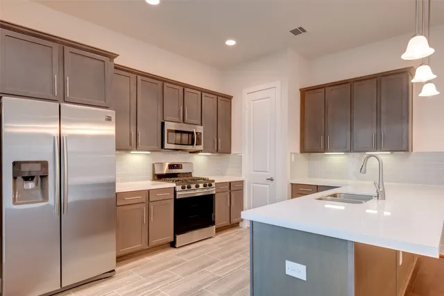 a kitchen with stainless steel appliances a sink a stove a refrigerator cabinets and a counter top space