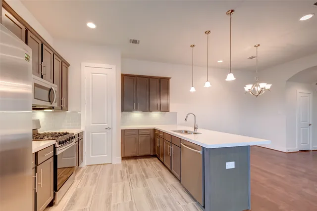 a kitchen with stainless steel appliances granite countertop a sink a stove and a wooden floors