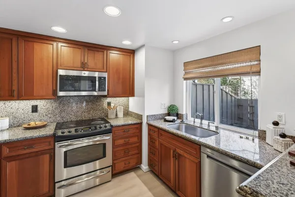 a kitchen with stainless steel appliances granite countertop wooden cabinets stove and sink