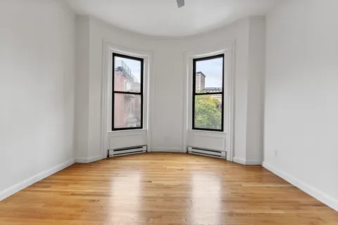 a view of empty room with window and wooden floor