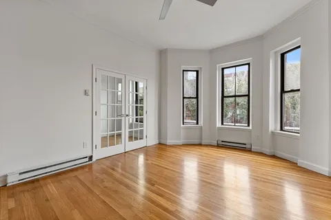 a view of an empty room with glass door and wooden floor