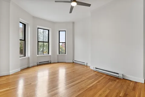 a view of an empty room with window and wooden floor