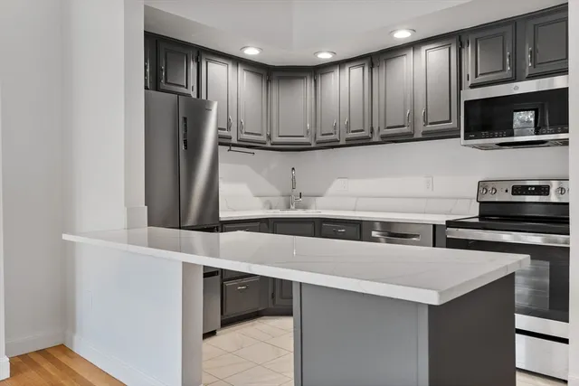 a kitchen with stainless steel appliances granite countertop a refrigerator and a stove top oven