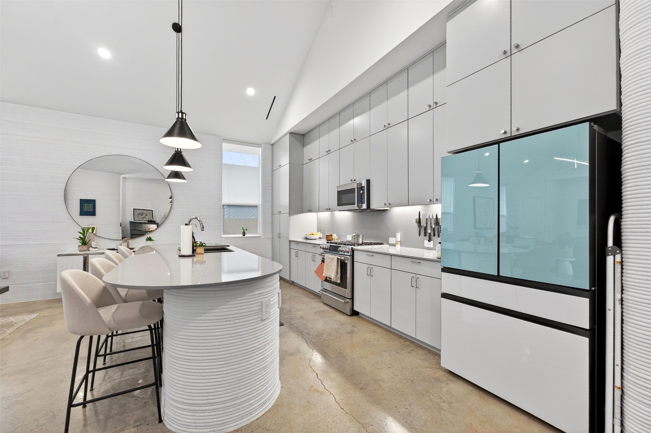 308 Painted Sunset Drive Georgetown, TX 78628 - Photo 8 of 26 Modern kitchen featuring a curved island with integrated sink, light gray cabinetry, stainless steel appliances, and concrete flooring