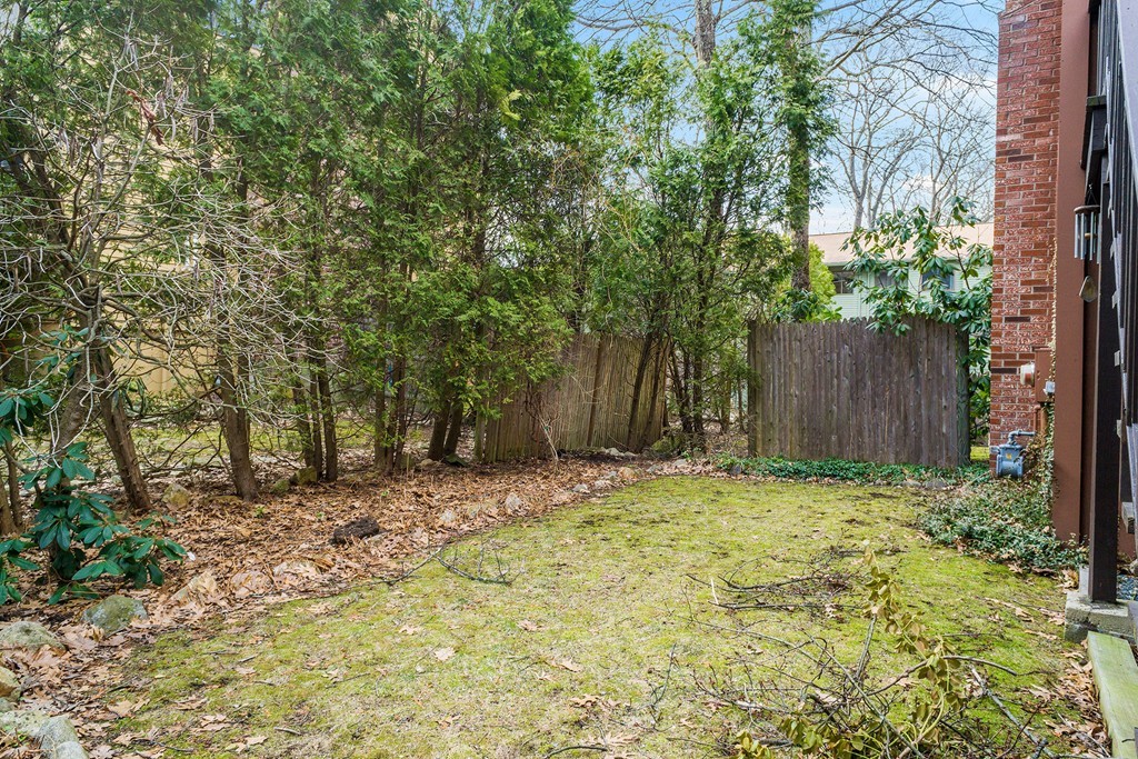 82 Meeting House Path, Unit 82 Ashland, MA 01721 - Photo 22 of 23 a small yard with large trees and wooden fence