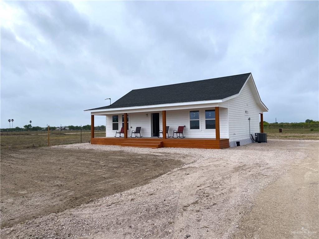 8101 West Mile 5 Road Mission, TX 78574 - Photo 1 of 1 View of front facade with a shingled roof, cooling unit, a wooden deck, and driveway