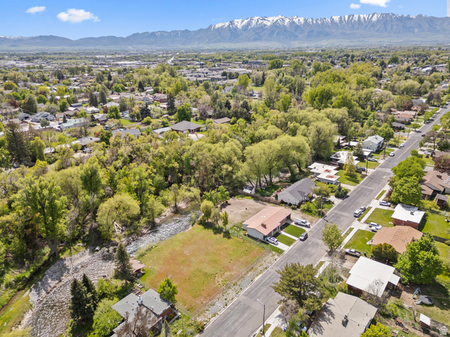 472 East 300 South Logan, UT 84321 - Photo 4 of 9 Expansive aerial capturing a suburban neighborhood with mature trees, a streetscape, and distant snow-capped mountains