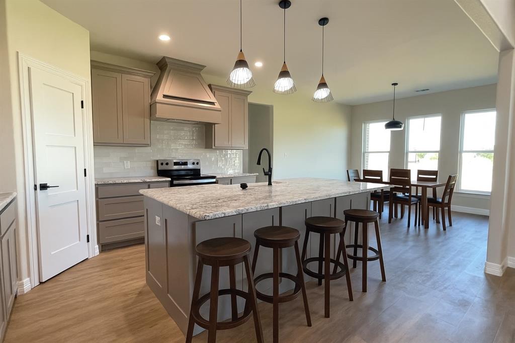 9771 Dripping Spring Road Denison, TX 75021 - Photo 3 of 4 a kitchen with granite countertop a stove a sink a dining table and chairs