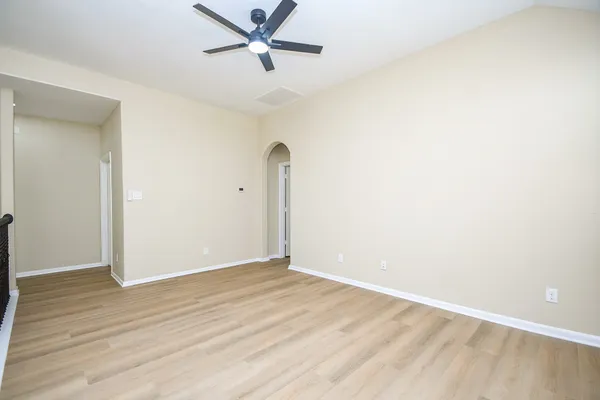 a view of an empty room with wooden floor and a window
