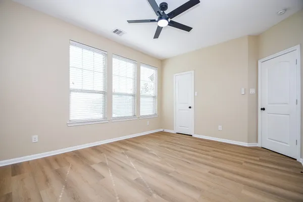 a view of empty room with wooden floor and fan