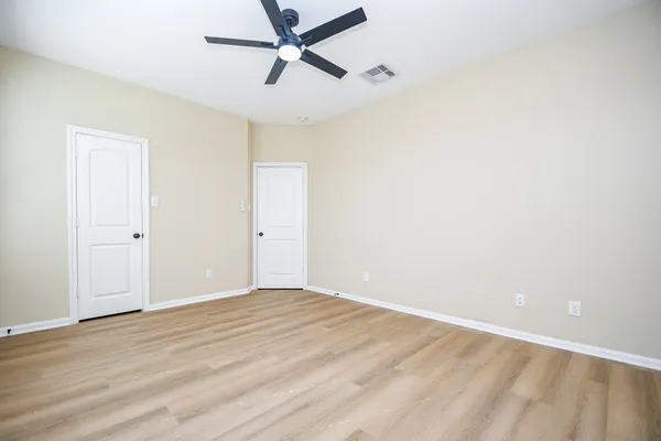 a view of a room with wooden floor and a ceiling fan