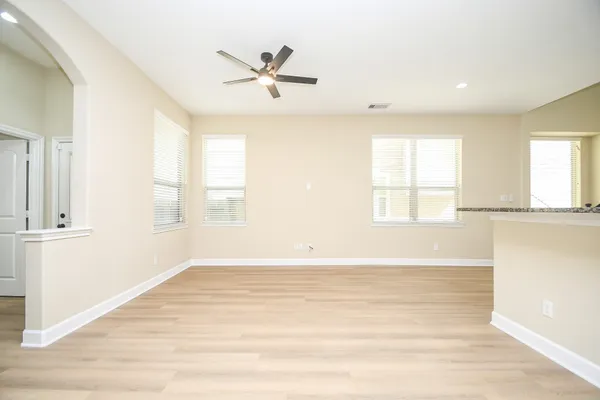 an empty room with wooden floor fan and windows