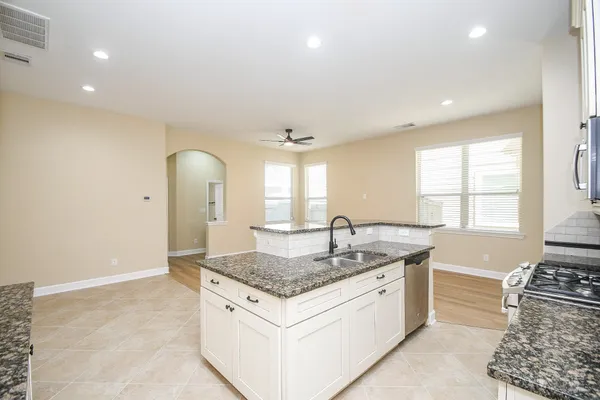 a kitchen with stainless steel appliances granite countertop a refrigerator sink and white cabinets