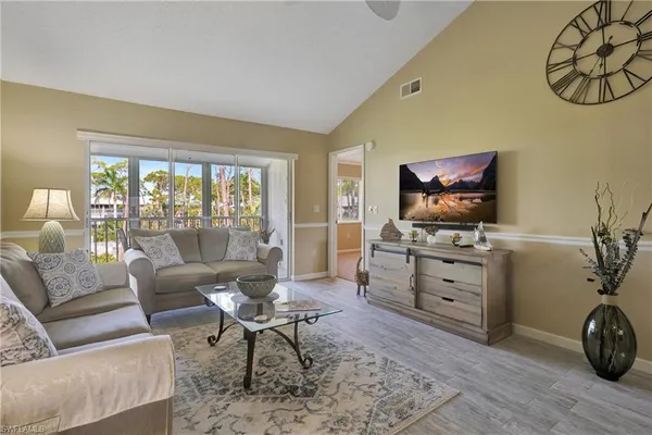 a living room with furniture a flat screen tv and large window