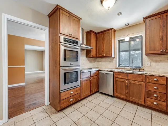 a kitchen with stainless steel appliances granite countertop a refrigerator and a stove top oven